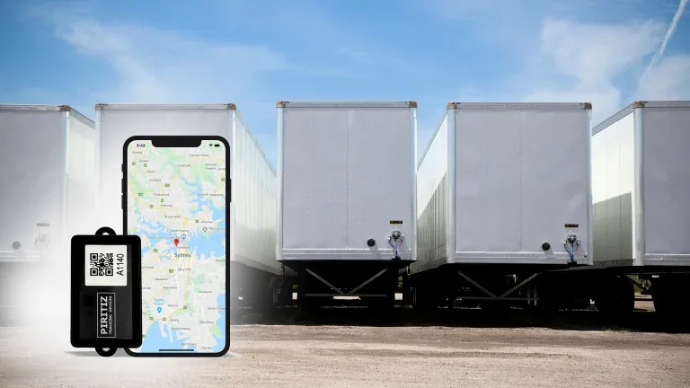 Rastreador Piritiz y teléfono con un mapa junto a una fila de remolques estacionados